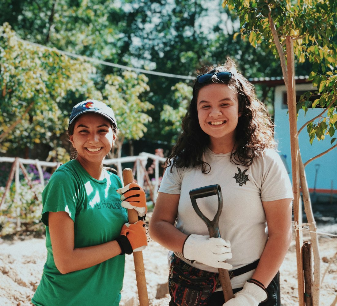 Two smiling volunteers holding shovels after planting a tree